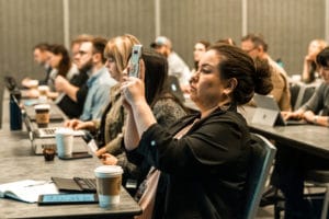 Lady at a conference capturing a photo of the speaker